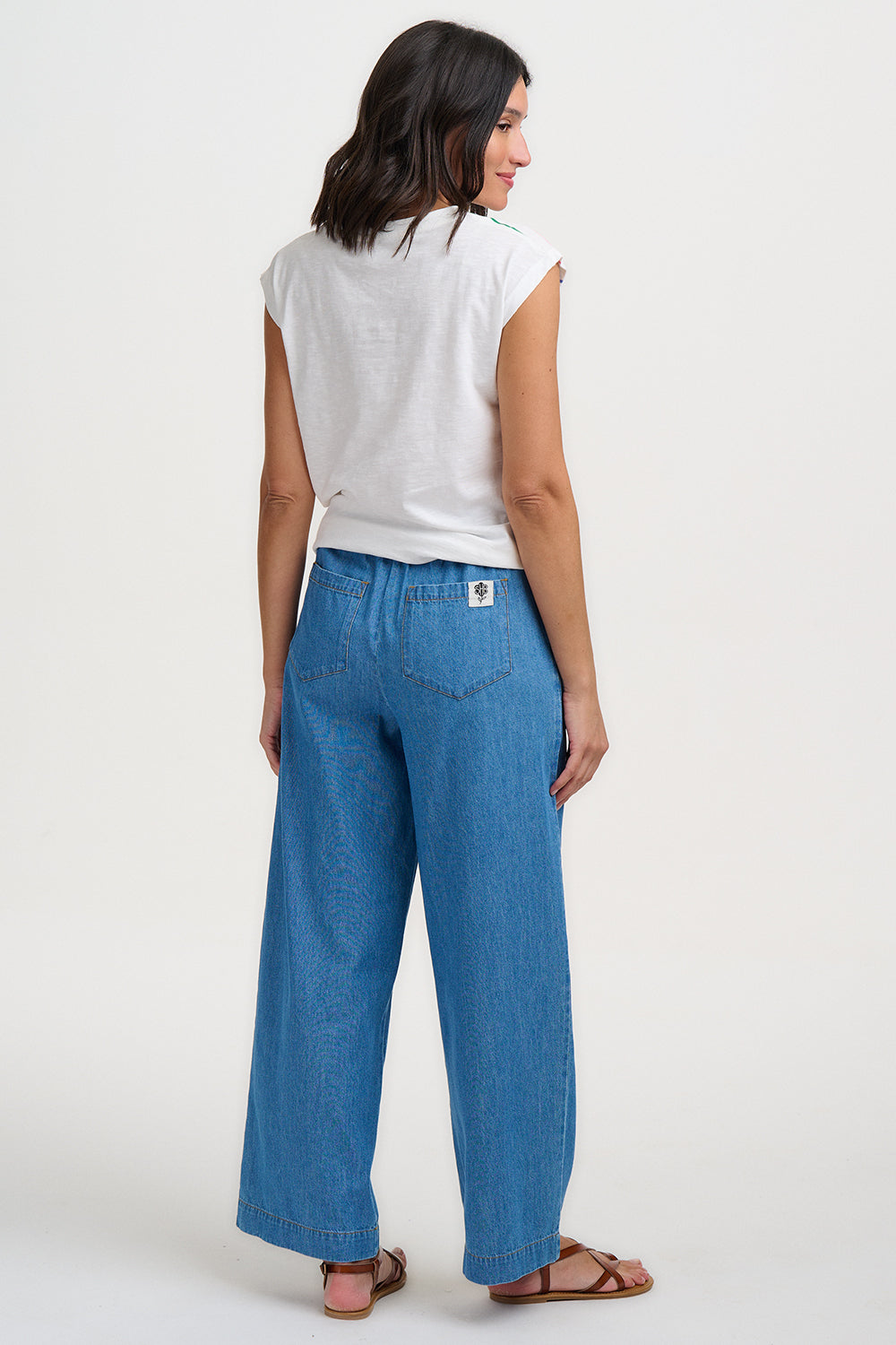 Woman wearing a white top and blue pants on a white background