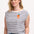 A woman wearing an off-white sleeveless tank top with navy stripes and a fruity orange embroidery on the chest.