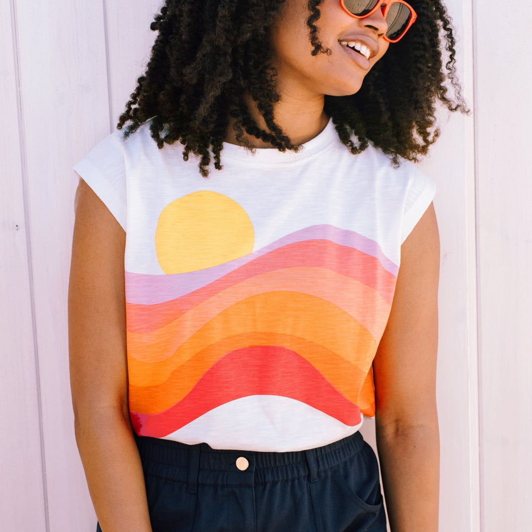 Woman wearing a sleeveless shirt with a colorful design against a white background