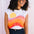 Woman wearing a sleeveless shirt with a colorful design against a white background