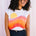 Woman wearing a sleeveless shirt with a colorful design against a white background