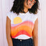 Woman wearing a sleeveless shirt with a colorful design against a white background