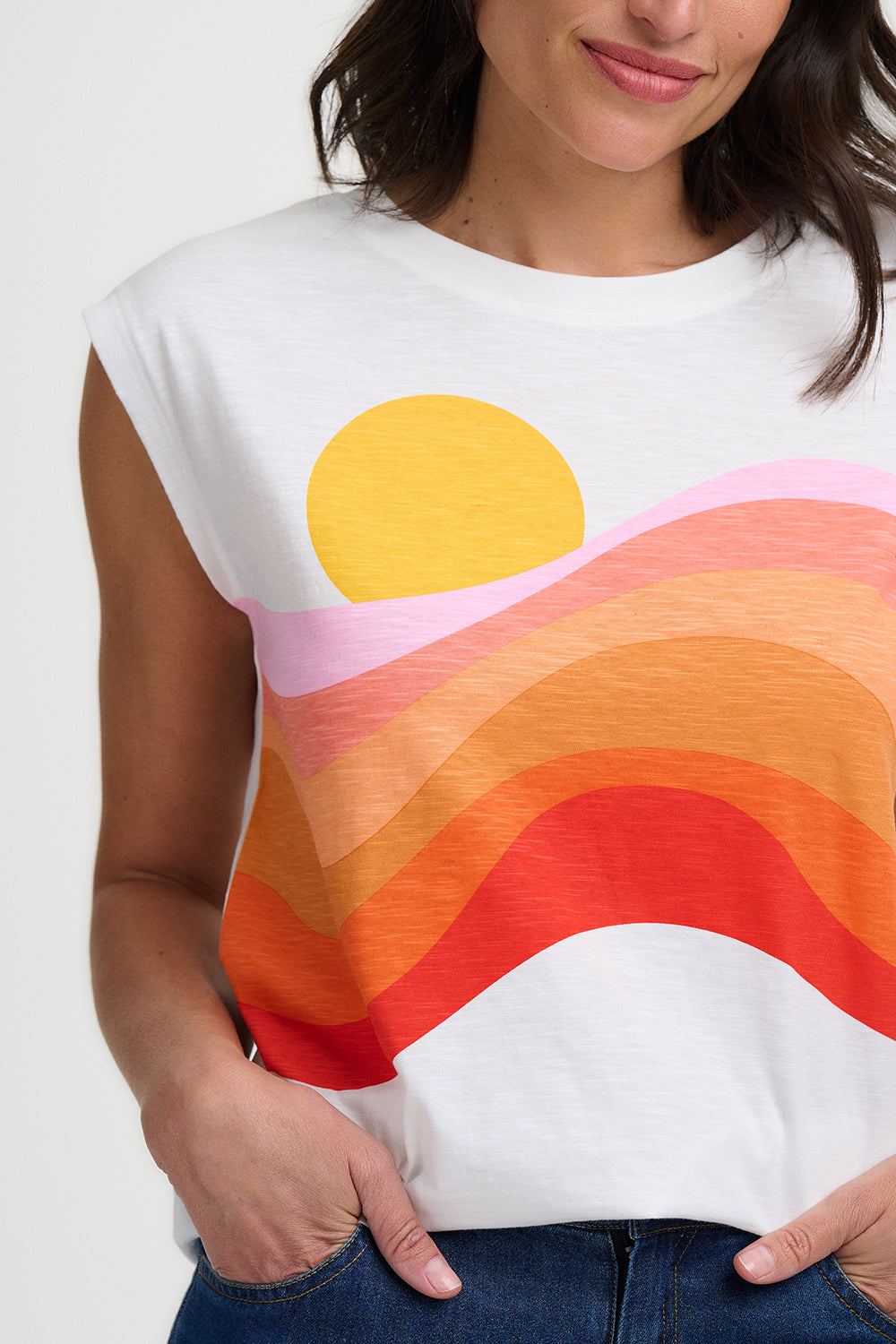 Woman wearing a white t-shirt with a colorful sun design on a plain background