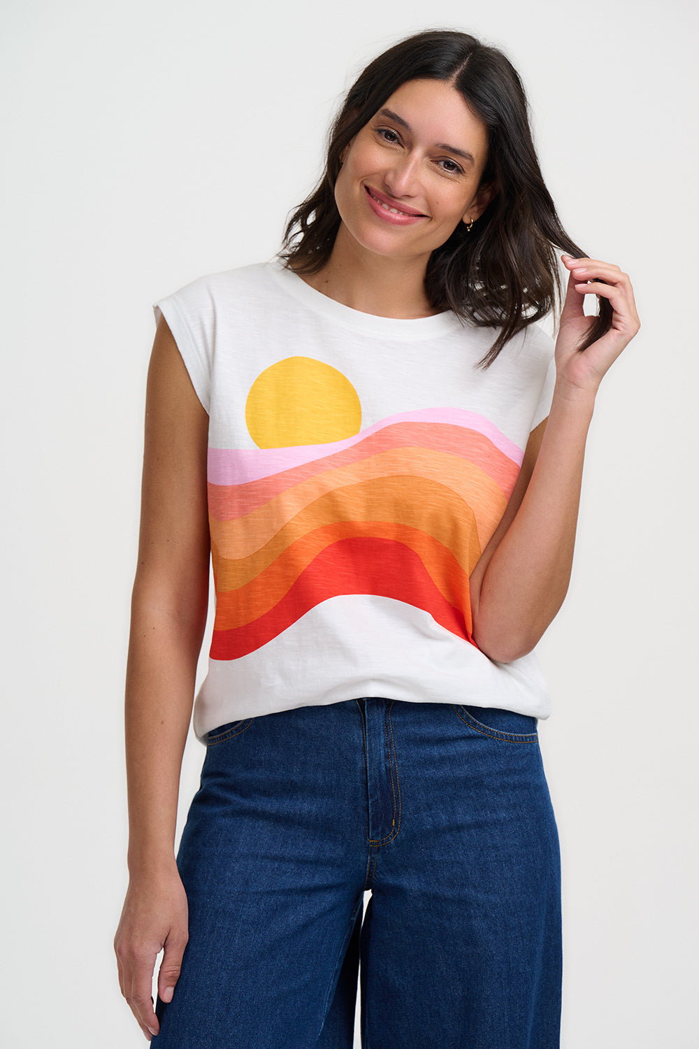 Woman wearing a sleeveless shirt with a colorful design on a plain background