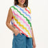 A woman modeling a sleeveless t-shirt with a geometric pattern of rainbow-colored waves on an off-white background.