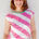 Woman wearing a pink and white striped sleeveless top against a light background