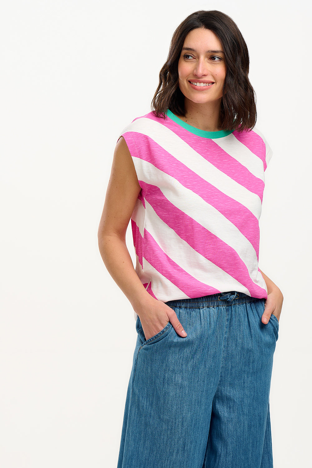 Sugarhill Brighton t-shirt. A female model wearing an oversized sleeveless striped t-shirt in pink and white, paired with blue jeans.