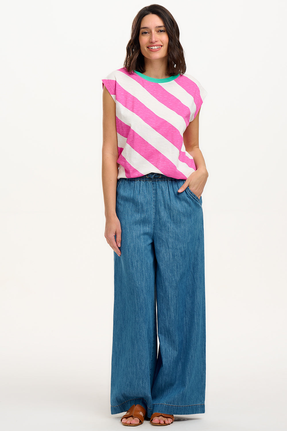Sugarhill Brighton t-shirt. A female model wearing an oversized sleeveless striped t-shirt in pink and white, paired with blue jeans.