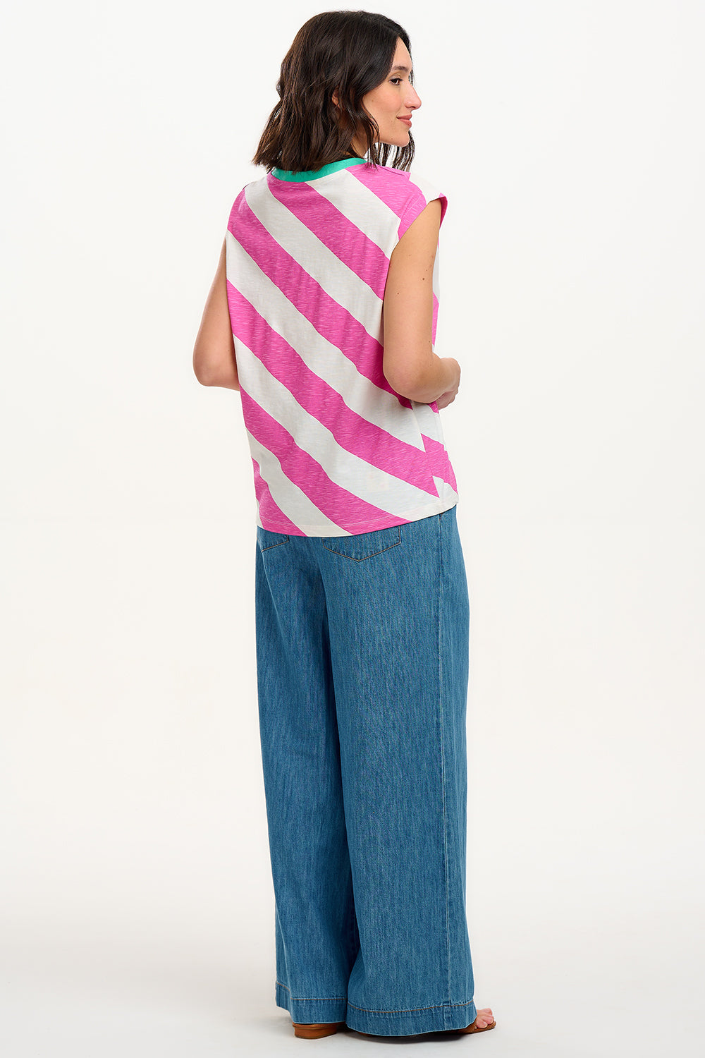 Sugarhill Brighton t-shirt. A female model wearing an oversized sleeveless striped t-shirt in pink and white, paired with blue jeans.