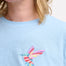 A woman wearing a pale blue sleeveless t-shirt with a tropical hummingbird graphic on the front