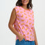 Woman wearing a pink sleeveless top with orange fruit pattern and blue pants on a white background