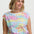 Woman wearing a colorful patterned top with a plain background