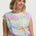 Woman wearing a colorful patterned top with a plain background