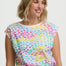 Woman wearing a colorful patterned top with a plain background