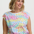 Woman wearing a colorful patterned top with a plain background