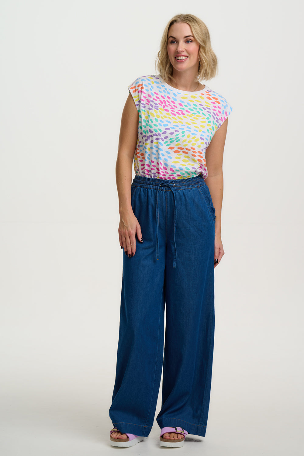 Woman wearing a colorful top and blue pants on a white background