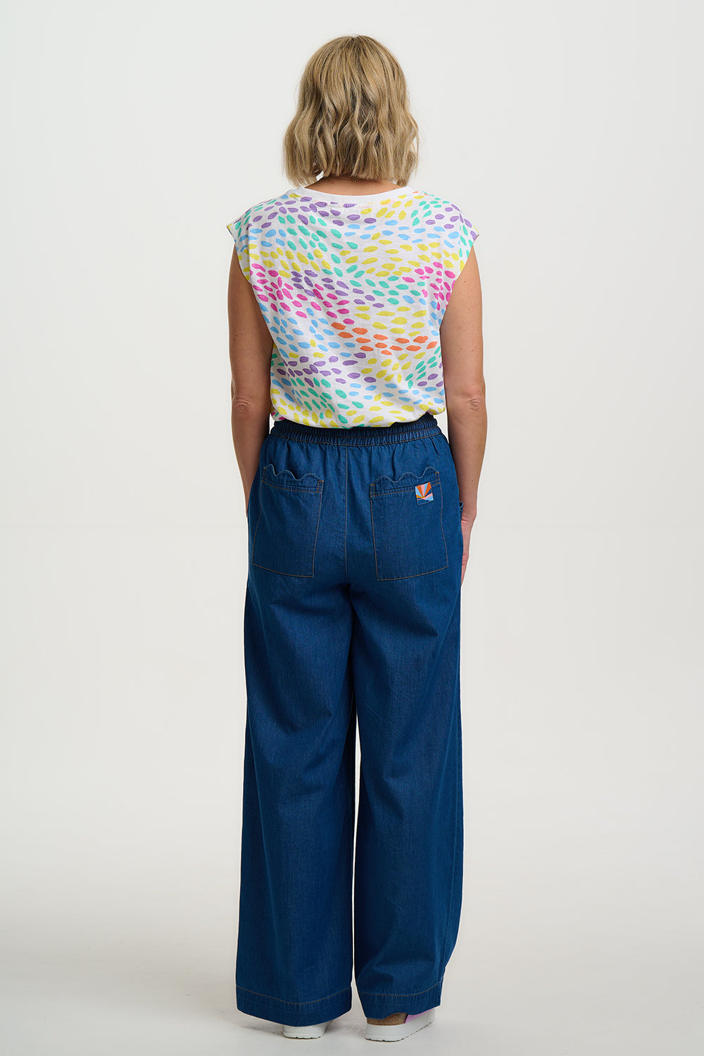 Person wearing a colorful patterned shirt and blue pants on a white background