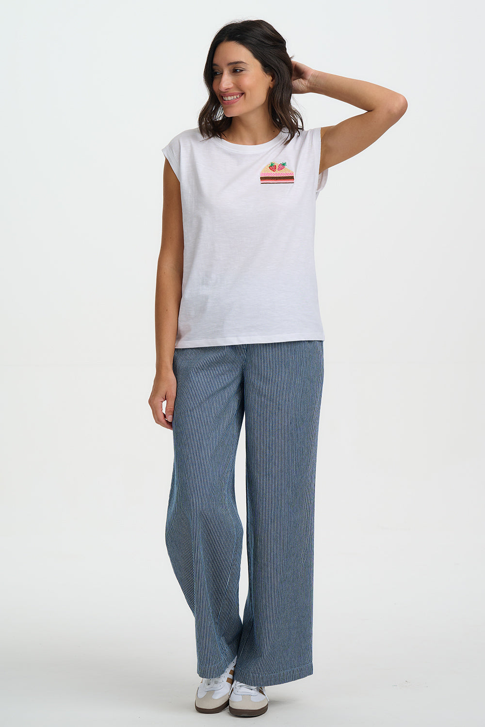 Woman wearing a white t-shirt with a logo and blue pants on a white background