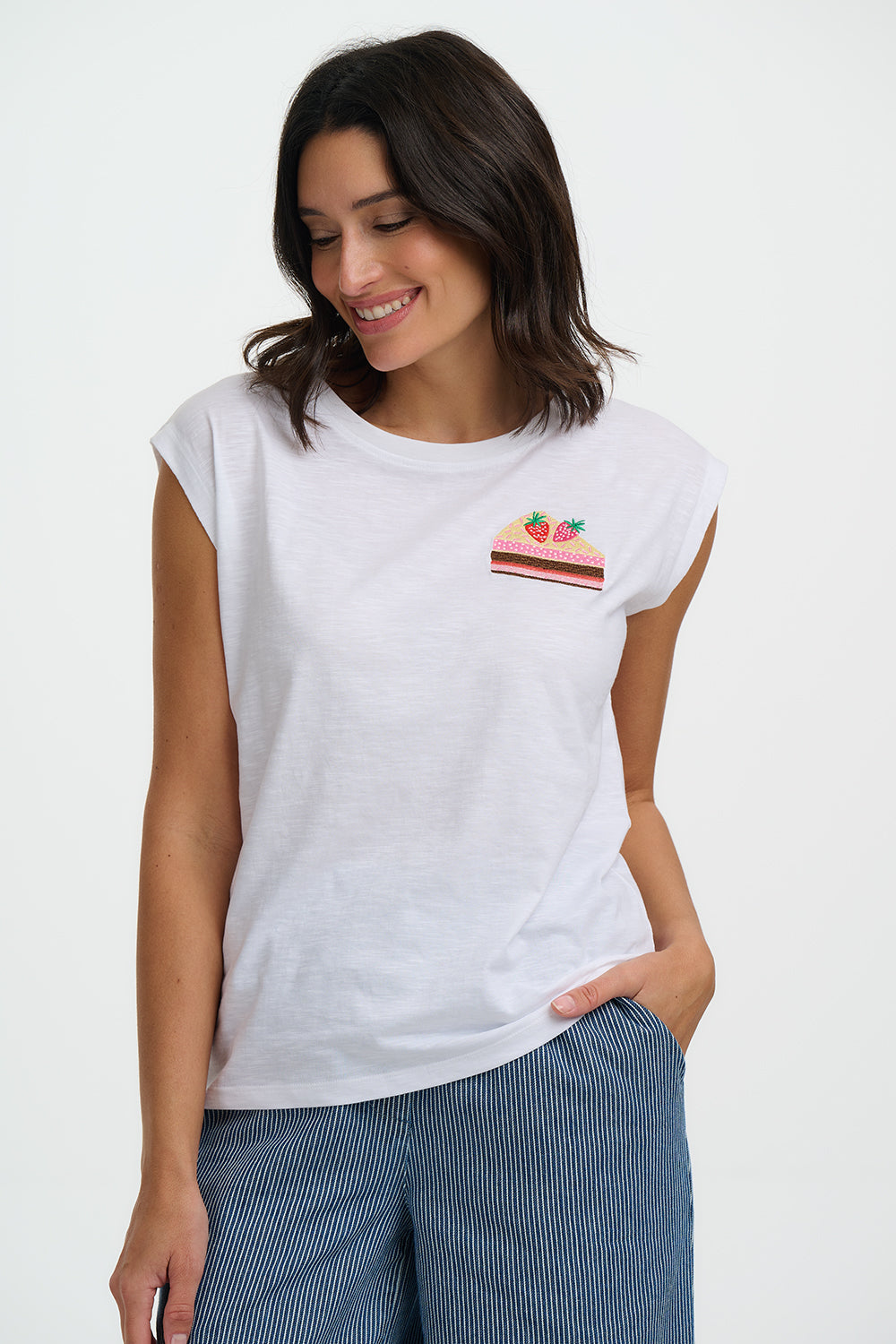 Woman wearing a white t-shirt with a small graphic on a plain background