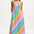 A woman wearing a multicolored rainbow checkerboard sundress with shirred top and midi length.
