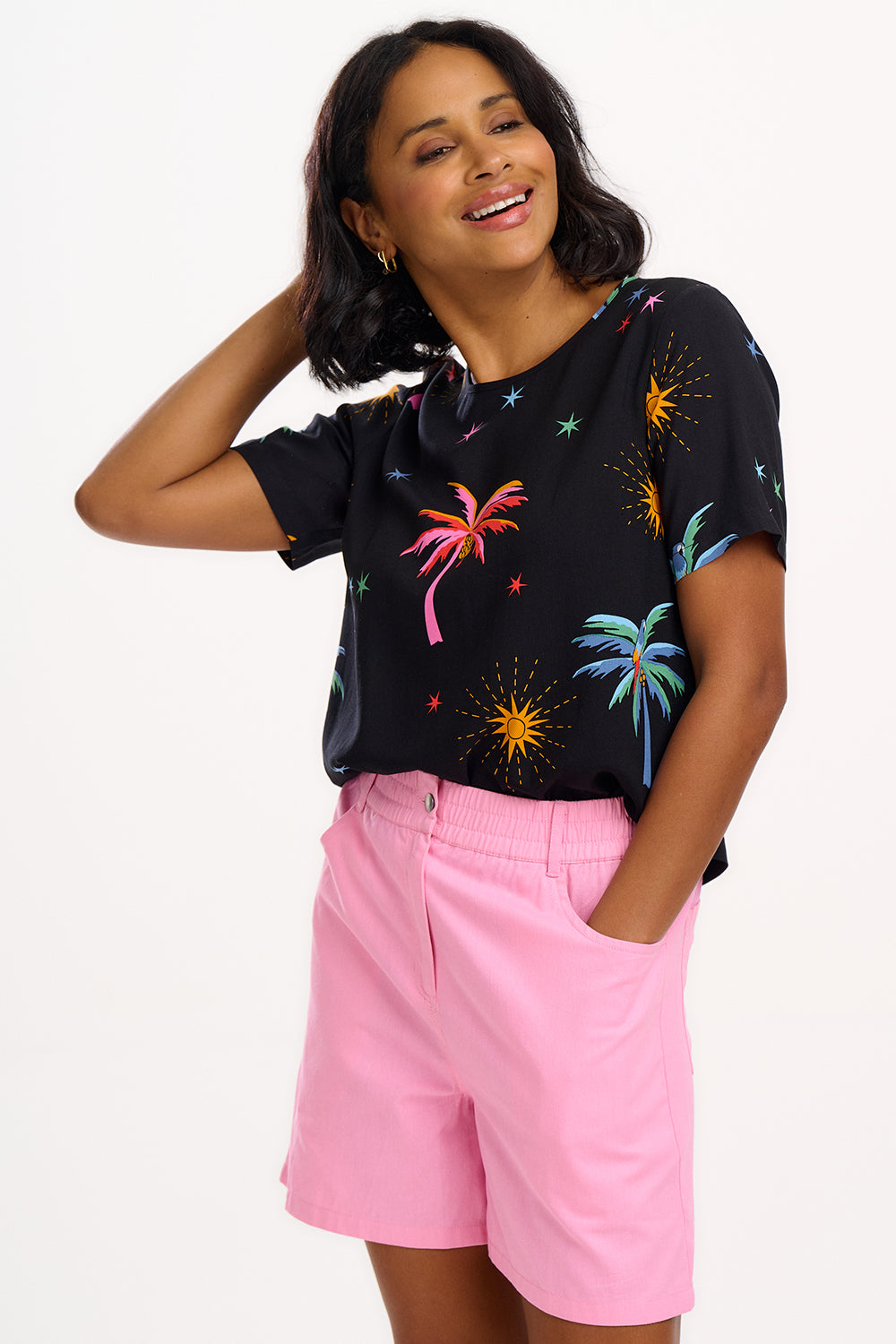 A woman wearing a black t-shirt with a colorful palm tree and star pattern, paired with blue denim jeans.
