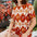 Woman wearing a patterned dress sitting outdoors with plants in the background