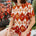 Woman wearing a patterned dress sitting outdoors with plants in the background