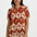 Woman wearing a patterned outfit with palm tree design on a plain background