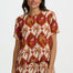 Woman wearing a patterned outfit with palm tree design on a plain background