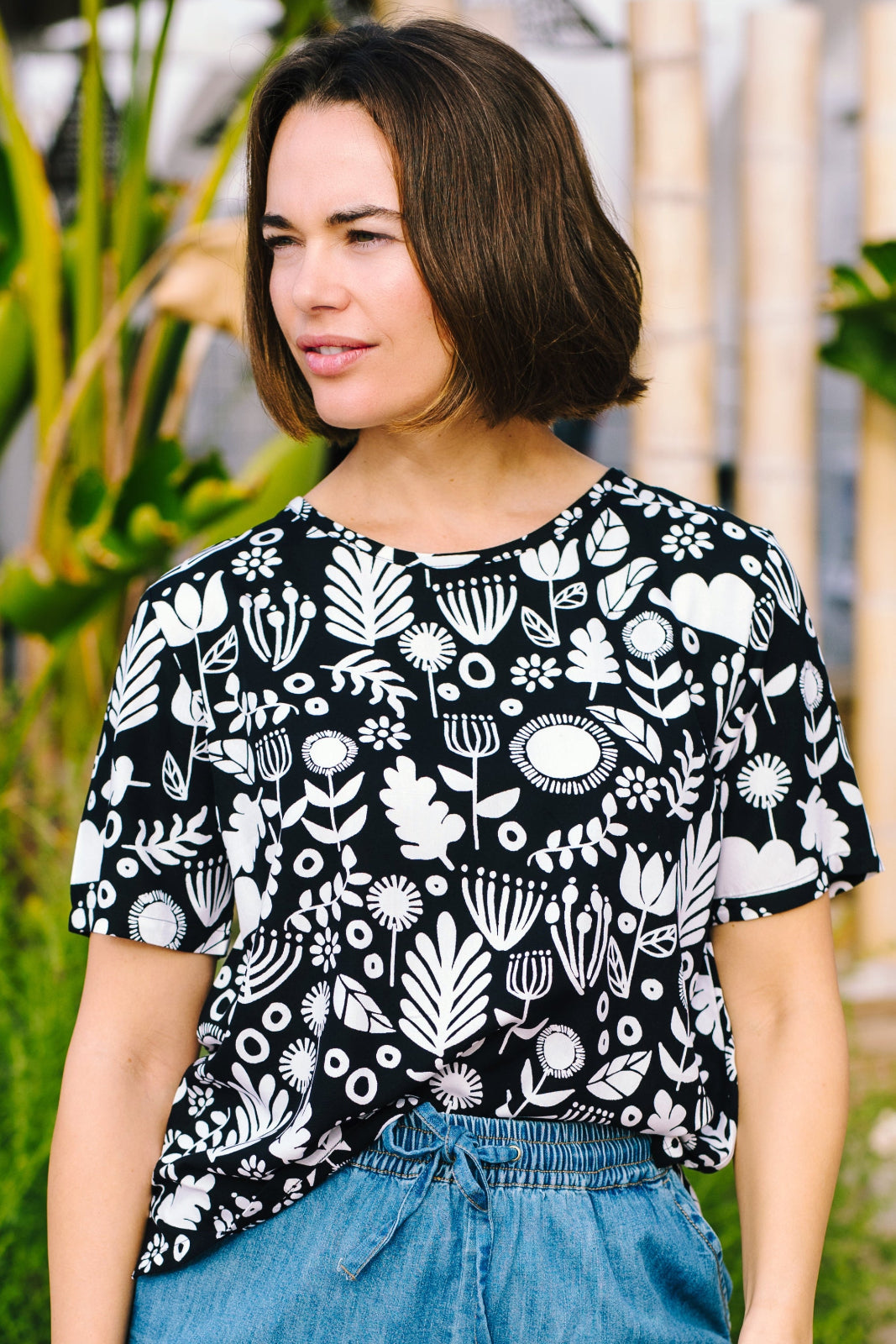 A woman wearing a black and white monochrome floral t-shirt with a crew neckline and side splits at the hem.