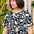 A woman wearing a black and white monochrome floral t-shirt with a crew neckline and side splits at the hem.