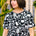 A woman wearing a black and white monochrome floral t-shirt with a crew neckline and side splits at the hem.