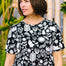 A woman wearing a black and white monochrome floral t-shirt with a crew neckline and side splits at the hem.