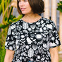 A woman wearing a black and white monochrome floral t-shirt with a crew neckline and side splits at the hem.