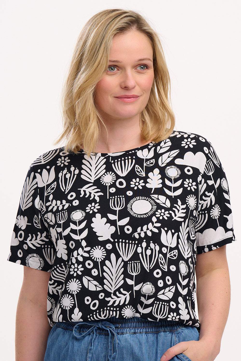 A woman wearing a black and white monochrome floral t-shirt with a crew neckline and side splits at the hem.