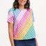 A woman smiling and wearing a multicolored rainbow checkerboard patterned t-shirt with a crew neckline and short sleeves.