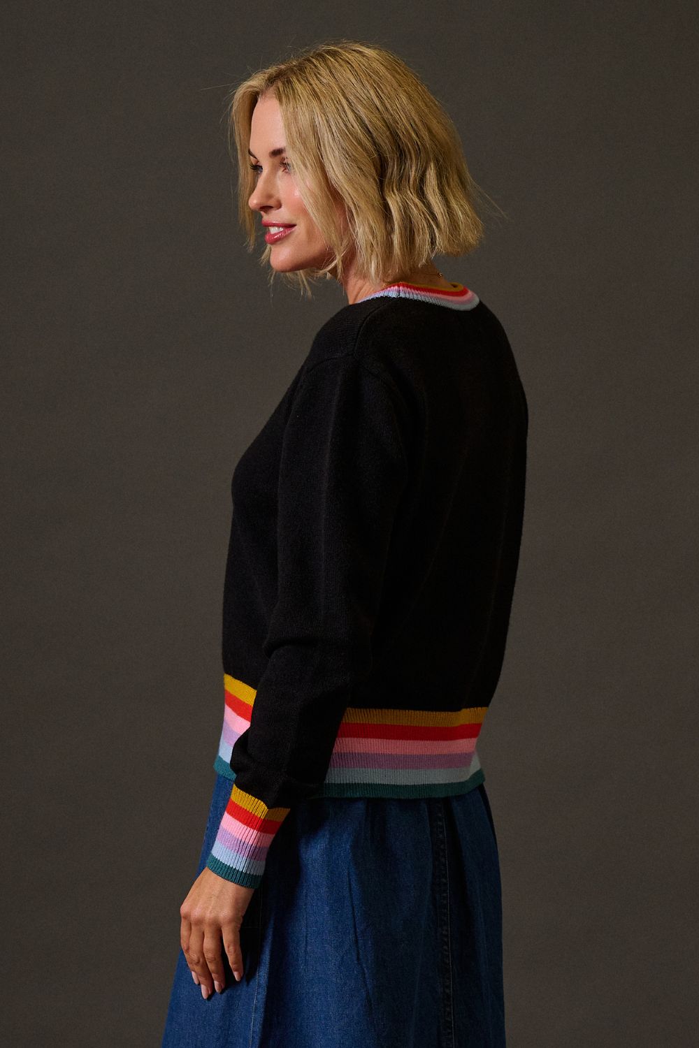 Woman wearing a black sweater with colorful stripes on a dark background