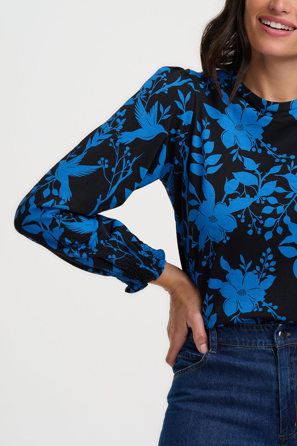 Person wearing a black and blue floral patterned top on a white background