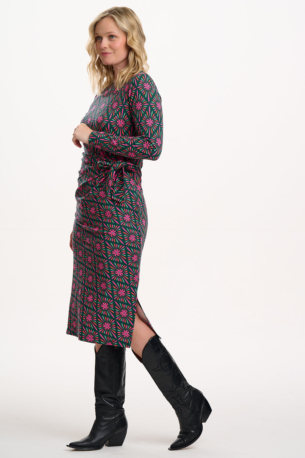 Sugarhill Brighton model wearing a patterned dress with black boots on a white background