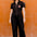 Woman wearing a black jumpsuit with a red heart design against an orange wall.
