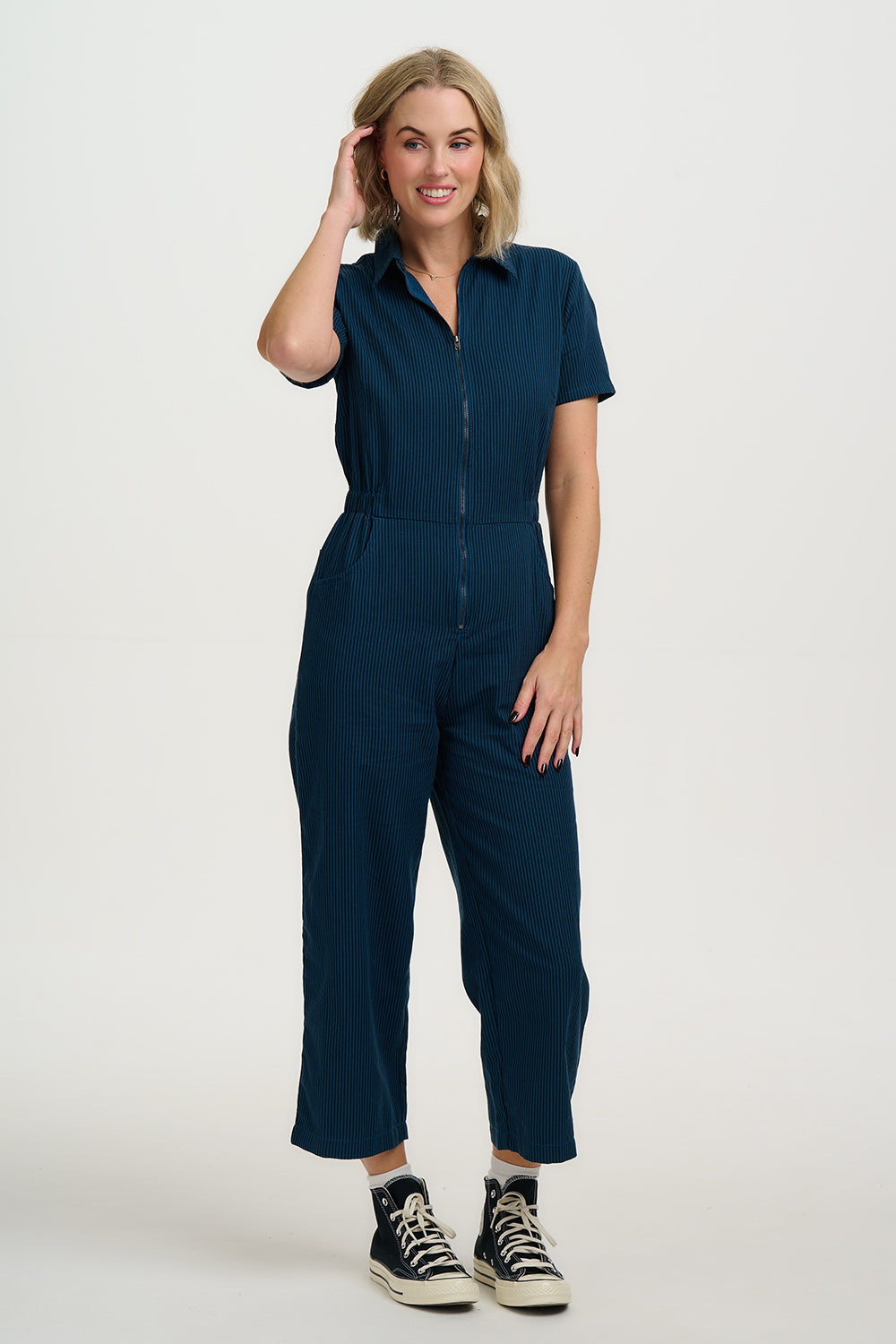 Woman wearing a navy blue jumpsuit on a white background