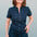 A woman smiling and posing in a navy jumpsuit with a black leopard print pattern, featuring short sleeves and wide flared legs.