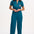 A woman modeling a teal-colored jumpsuit with short sleeves, a front zip, and wide flared legs. The jumpsuit features a pocket on the chest area and is embroidered with a rainbow parrot design.