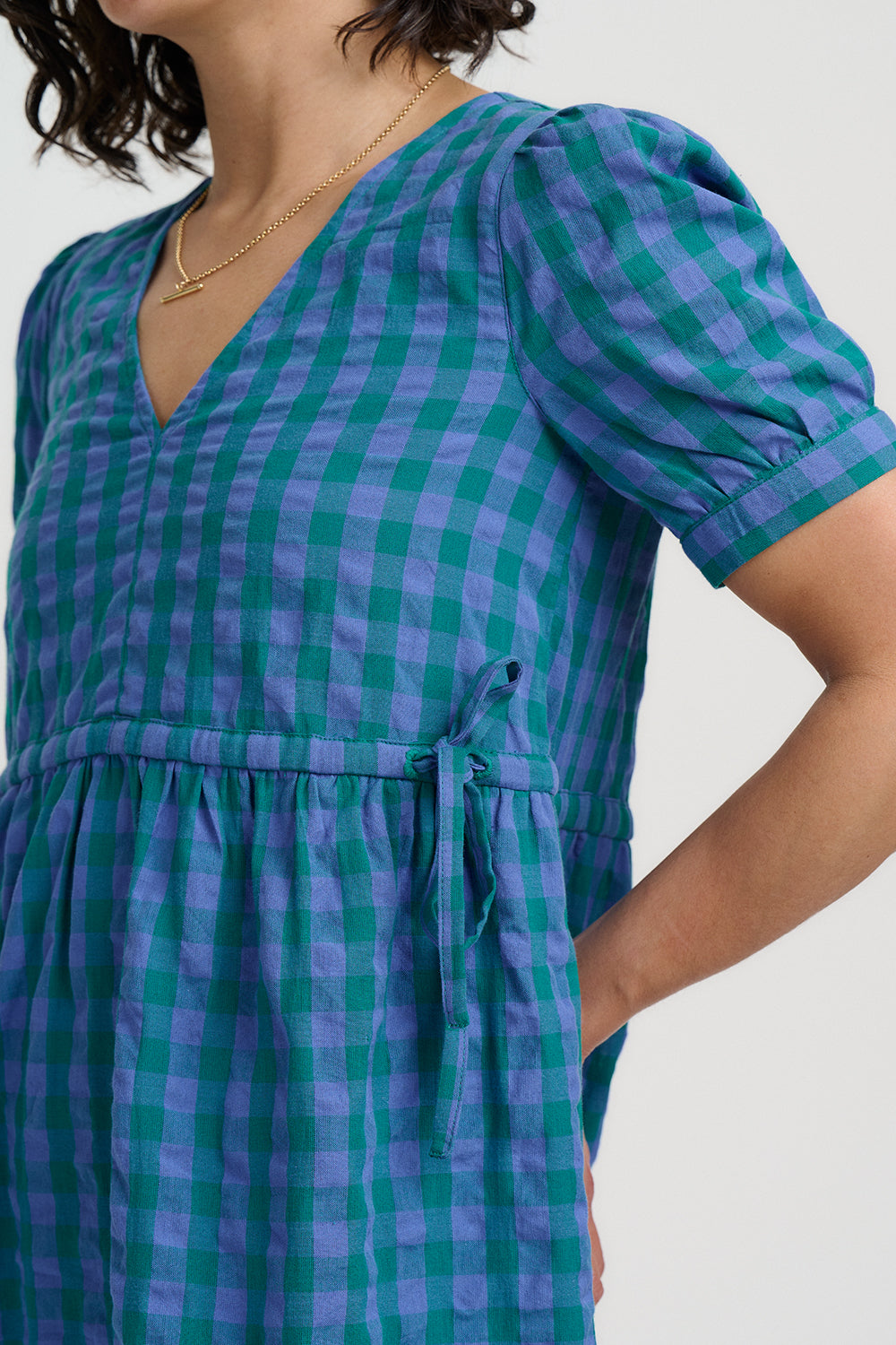 Woman wearing a blue and green checkered dress on a plain background