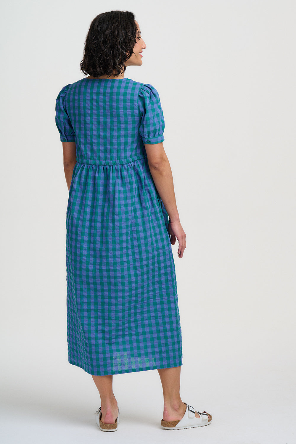 Woman wearing a blue checkered dress on a white background