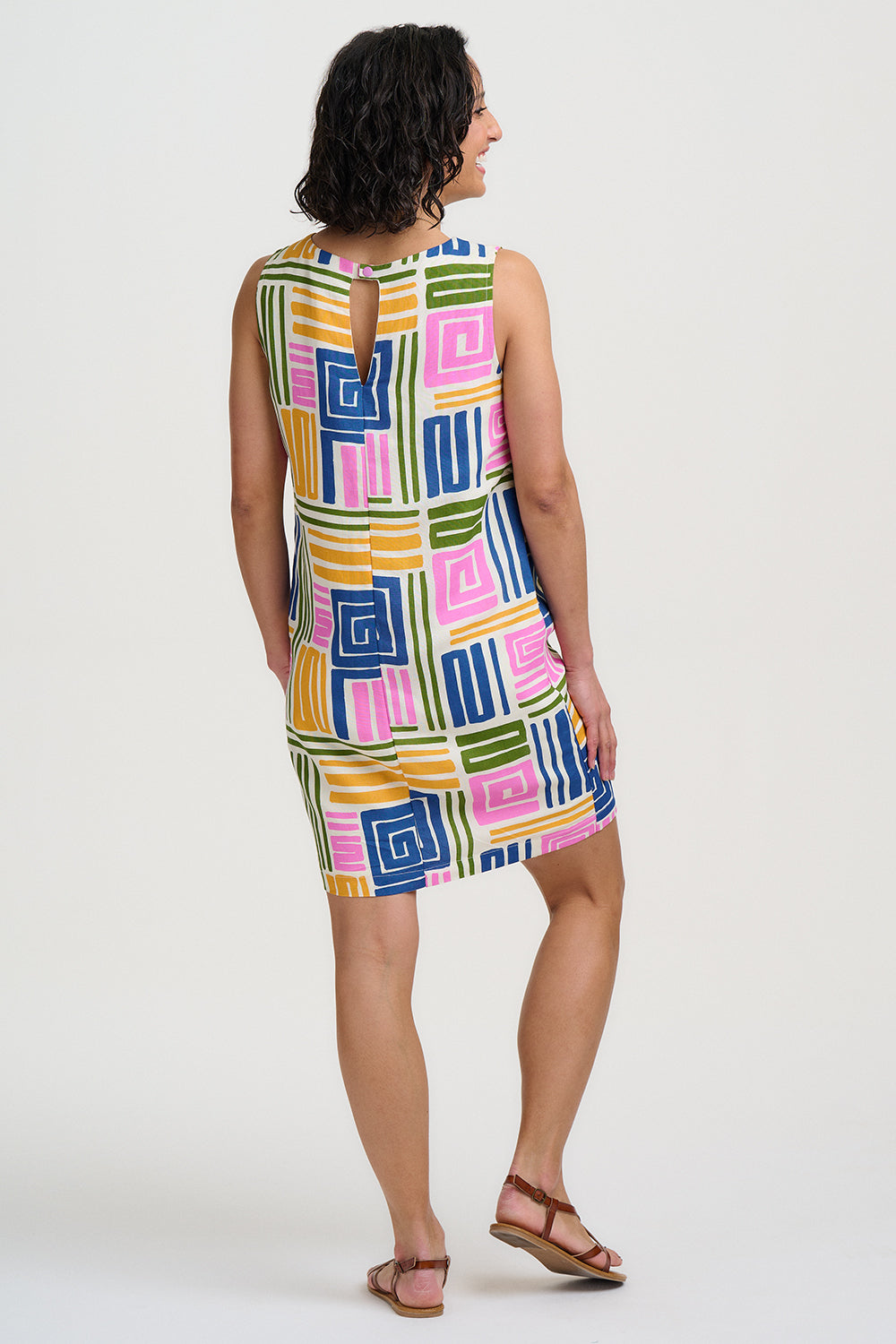 Woman wearing a colorful geometric-patterned dress on a white background