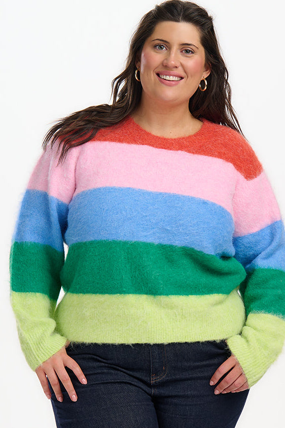 Person wearing a colorful striped sweater and dark jeans on a white background