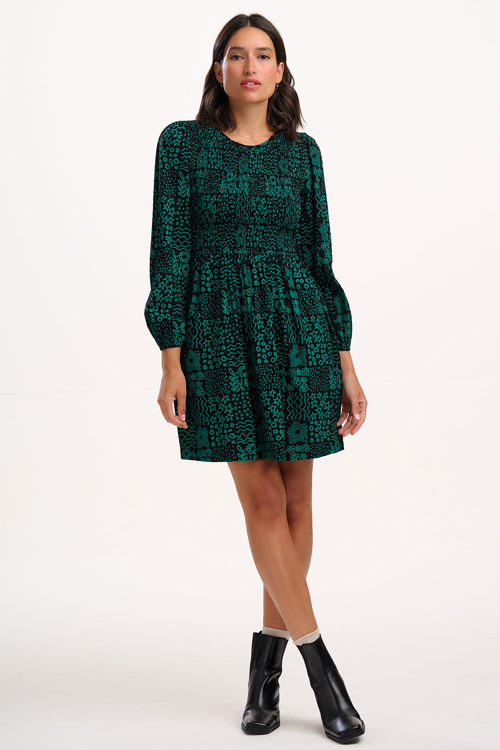 Woman wearing a green patterned dress on a white background