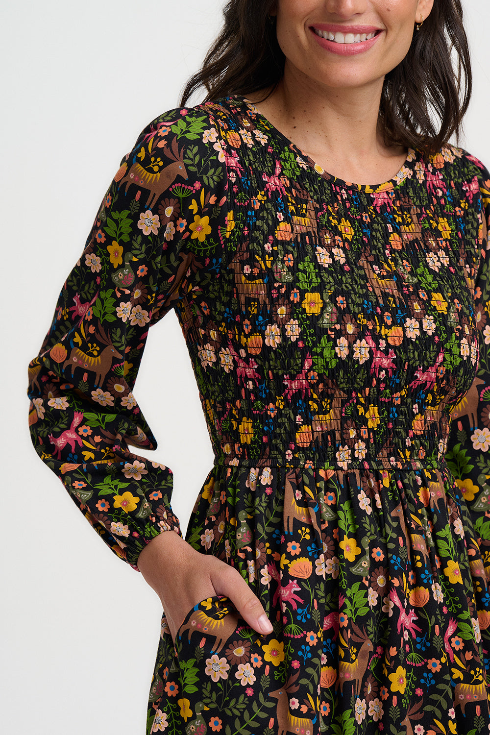 Woman wearing a long-sleeve dress with a colorful animal pattern on a white background