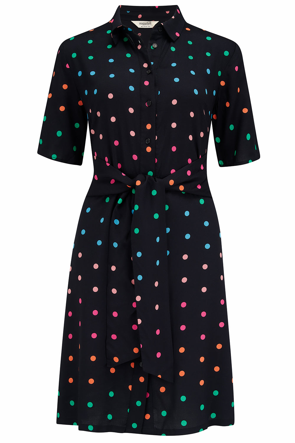 A black dress with colorful polka dots against a stone wall.